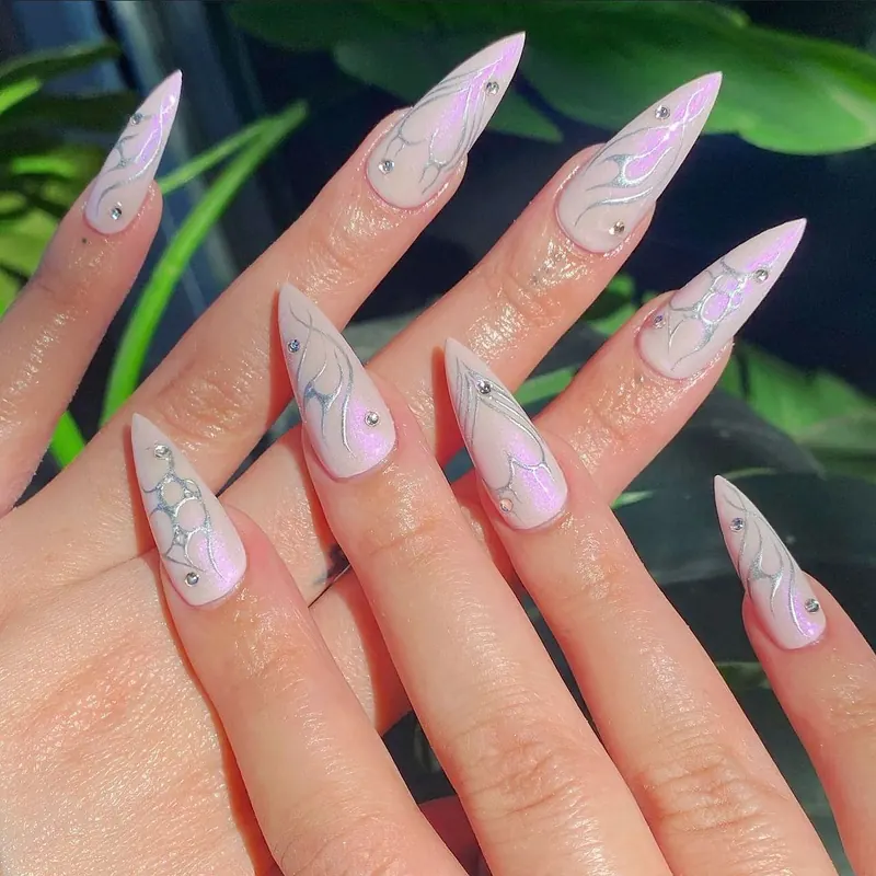 Milky aurora chrome stiletto nails with marble lines and crystals