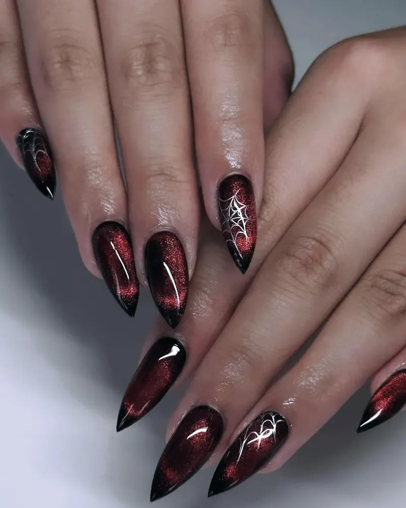 Burgundy cat-eye stiletto nails with silver spider-web art