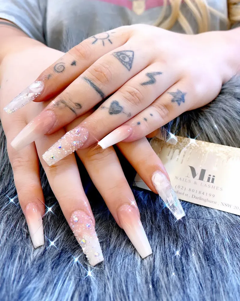 Nude-to-white ombré coffin nails with glitter and crystal accent nails