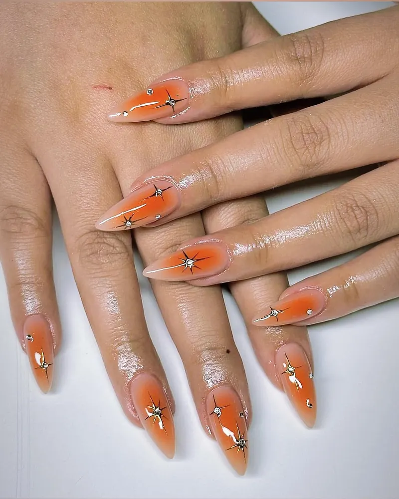 Orange airbrush aura almond nails with chrome star sparkles
