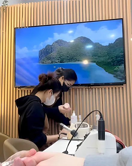 Nail technicians at work at the manicure desks under the wood-slat feature wall